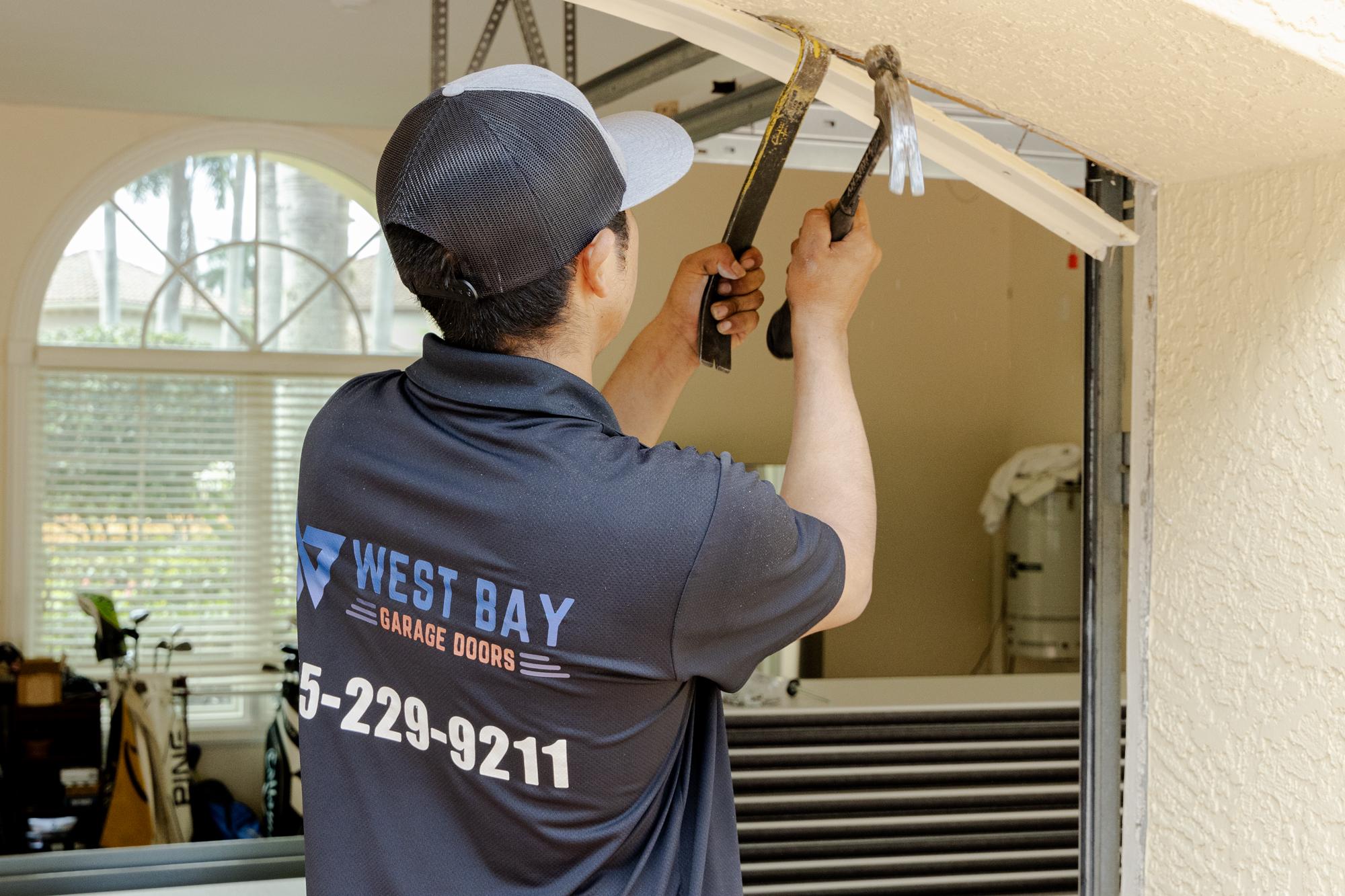 Worker pulling off trim to put up new garage door