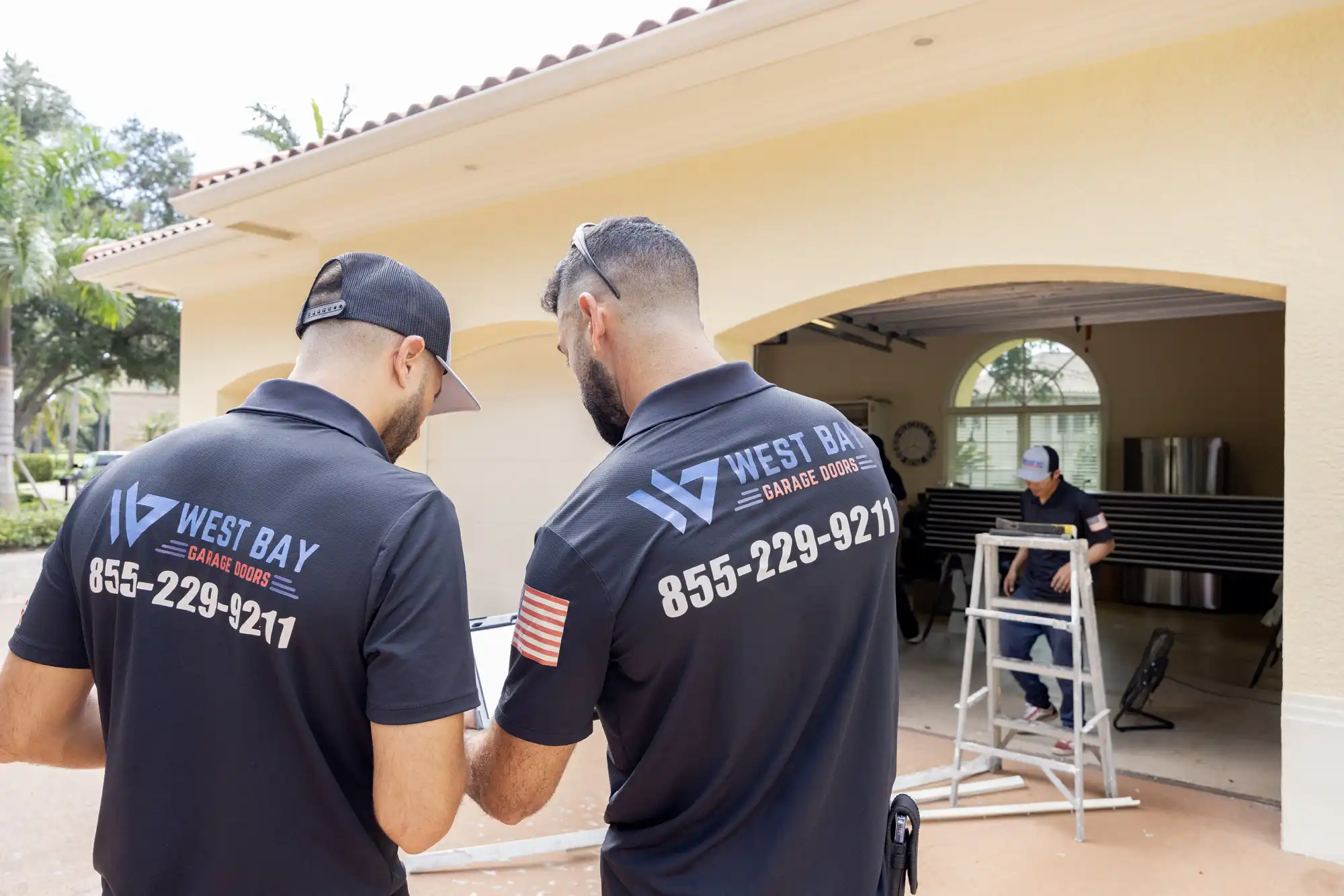 Two men in West Bay Garage uniforms looking over plans for install